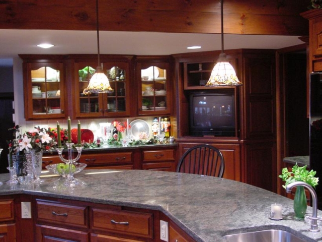 Custom cherry kitchen cabinets with glass doors in the Langhorne area of Lower Bucks County. Kitchen remodel. Our cabinets are set with LED lights and glass shelves. The island is custom on an angle for easy flow around the room with plenty of room for stools.