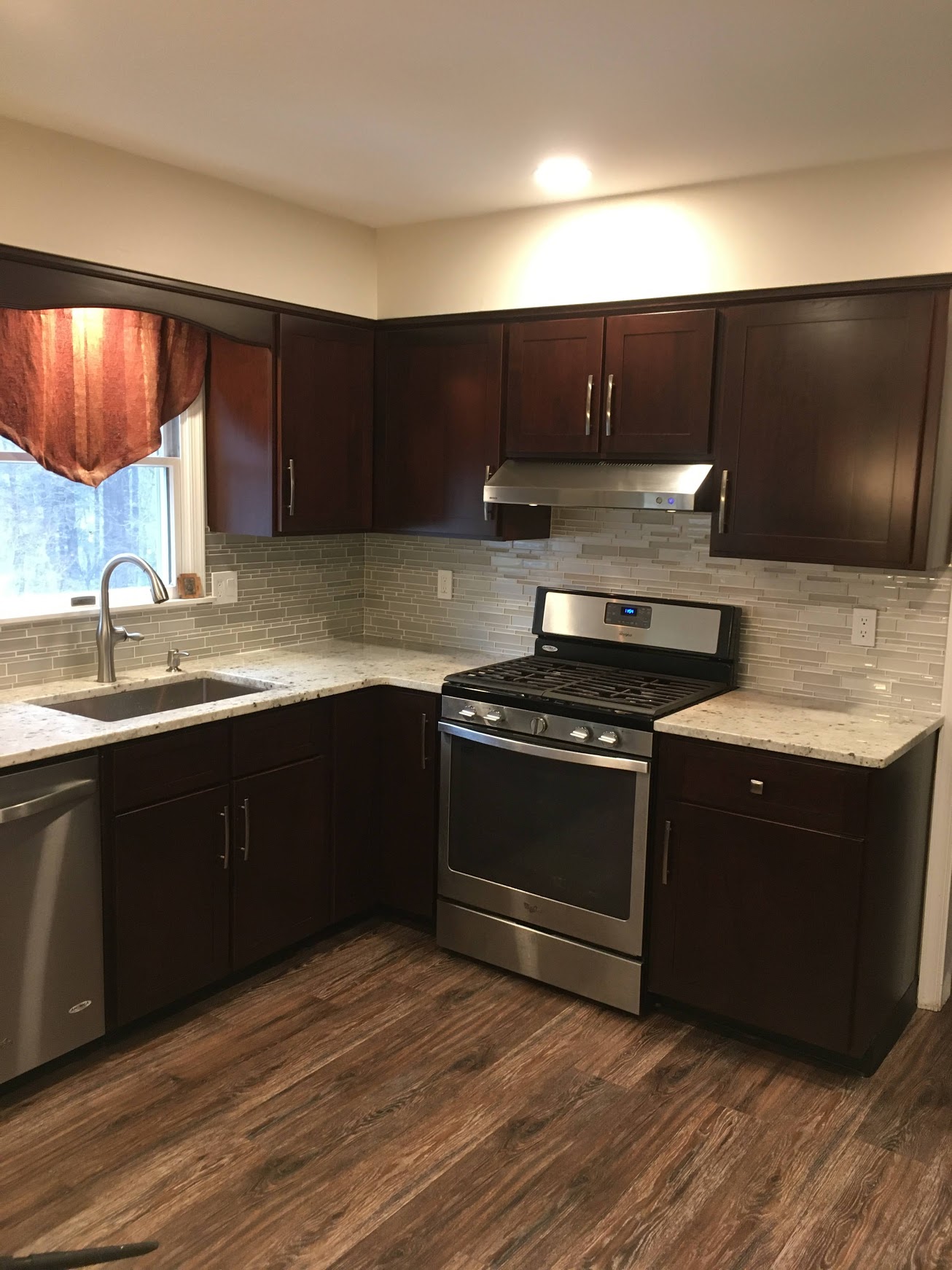 Beautiful kitchen cabinet refacing in Langhorne, PA with shaker style door and drawer fronts. The cabinetry is a cherrywood stained in a dark red wine hue. Quartz countertops, a stunning tile back splash and silver hardware wonderfully accent the new look.