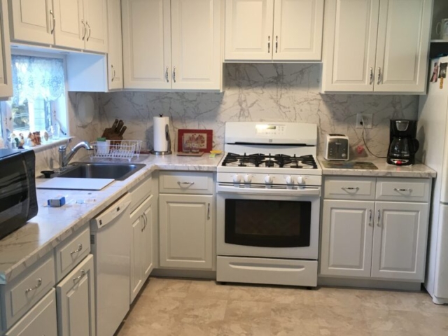White L shaped kitchen with white appliances and white an gray granite counter top